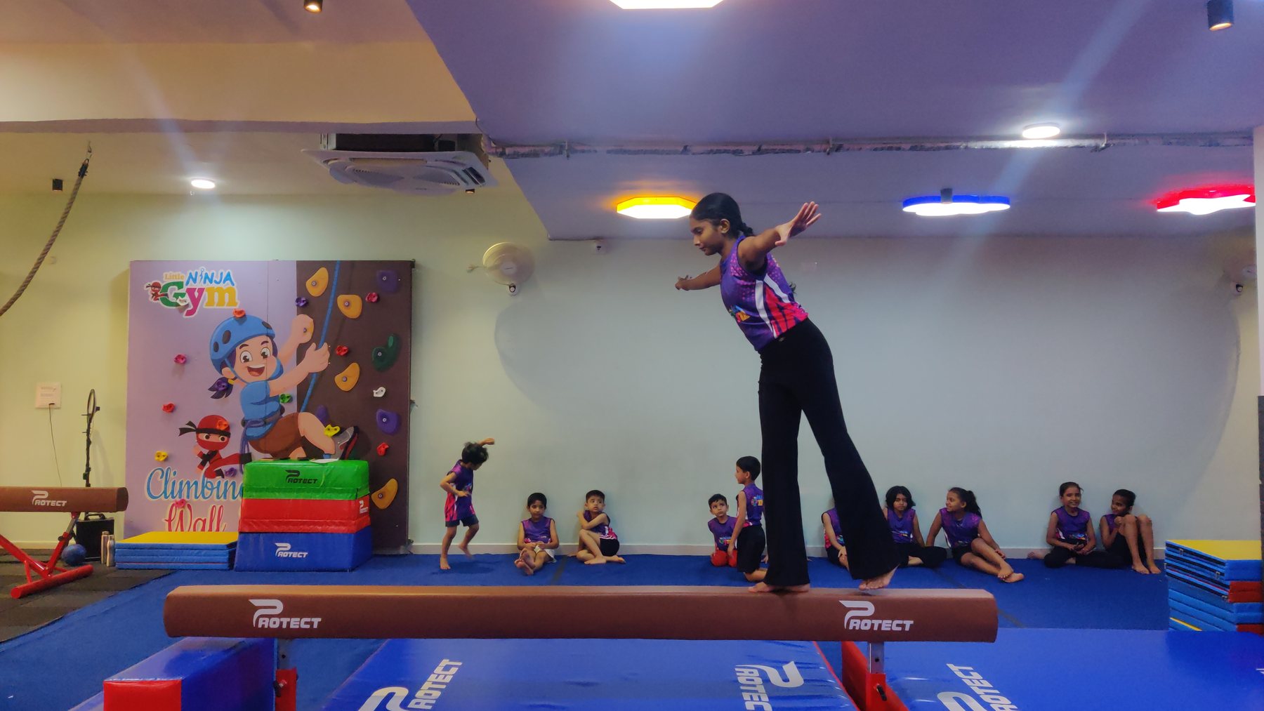 Children watching a balance beam gymnastics demonstration